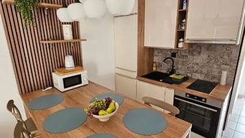 Una cocina moderna con una mesa de comedor de madera, un cuenco de fruta y un horno empotrado.
