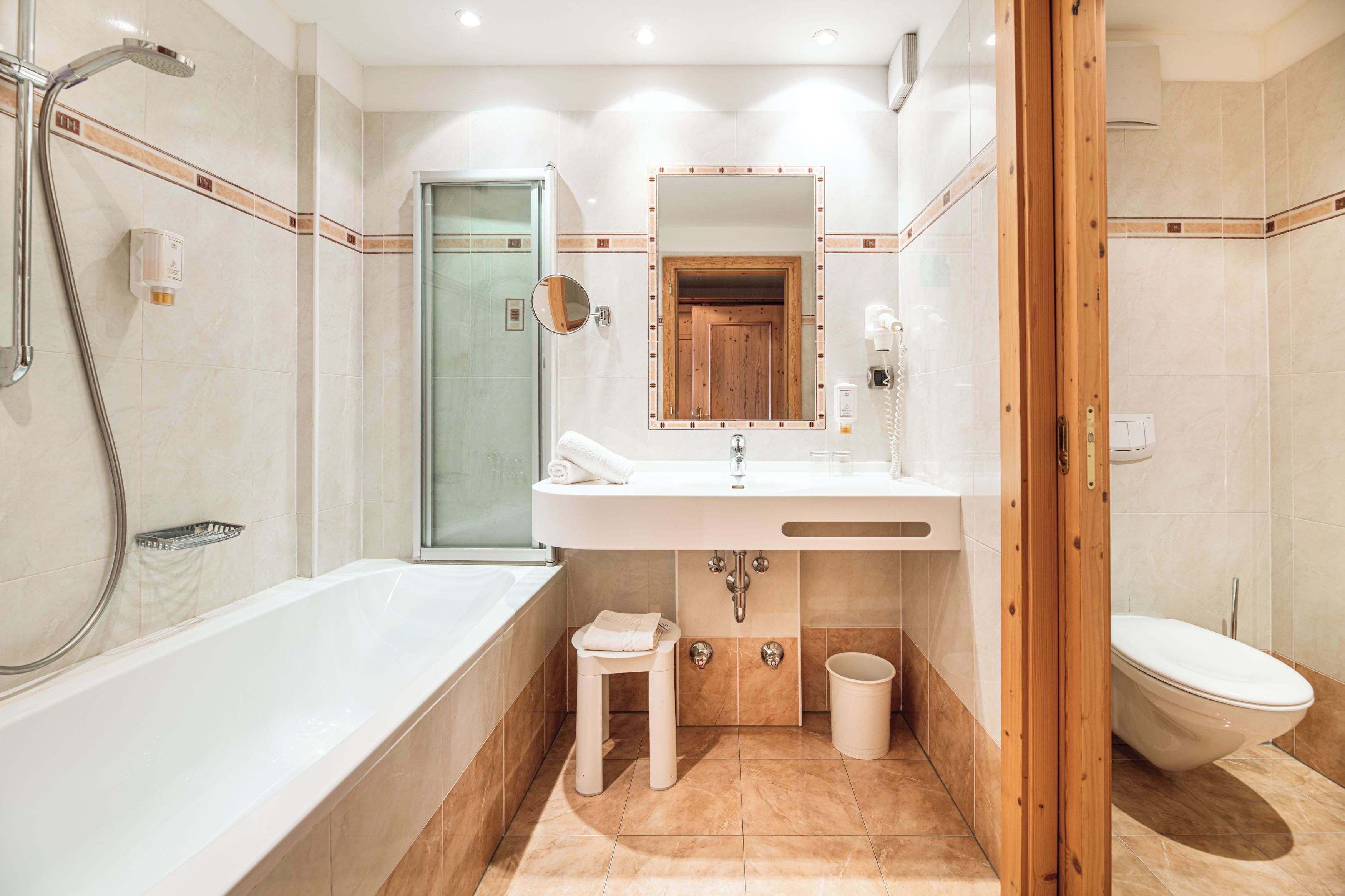 A modern bathroom with a bathtub, a sink with a mirror, a toilet, and a shower area.