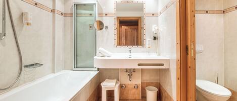 A modern bathroom with a bathtub, a sink with a mirror, a toilet, and a shower area.
