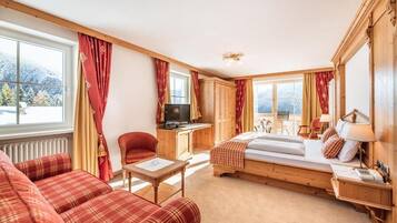 Een knus ingerichte kamer met een bed, bureau, televisie en een bank.