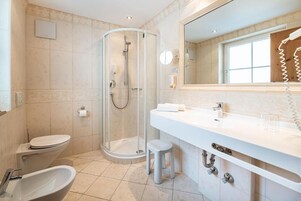 A modern bathroom with a glass-enclosed shower, a white sink, and a toilet.