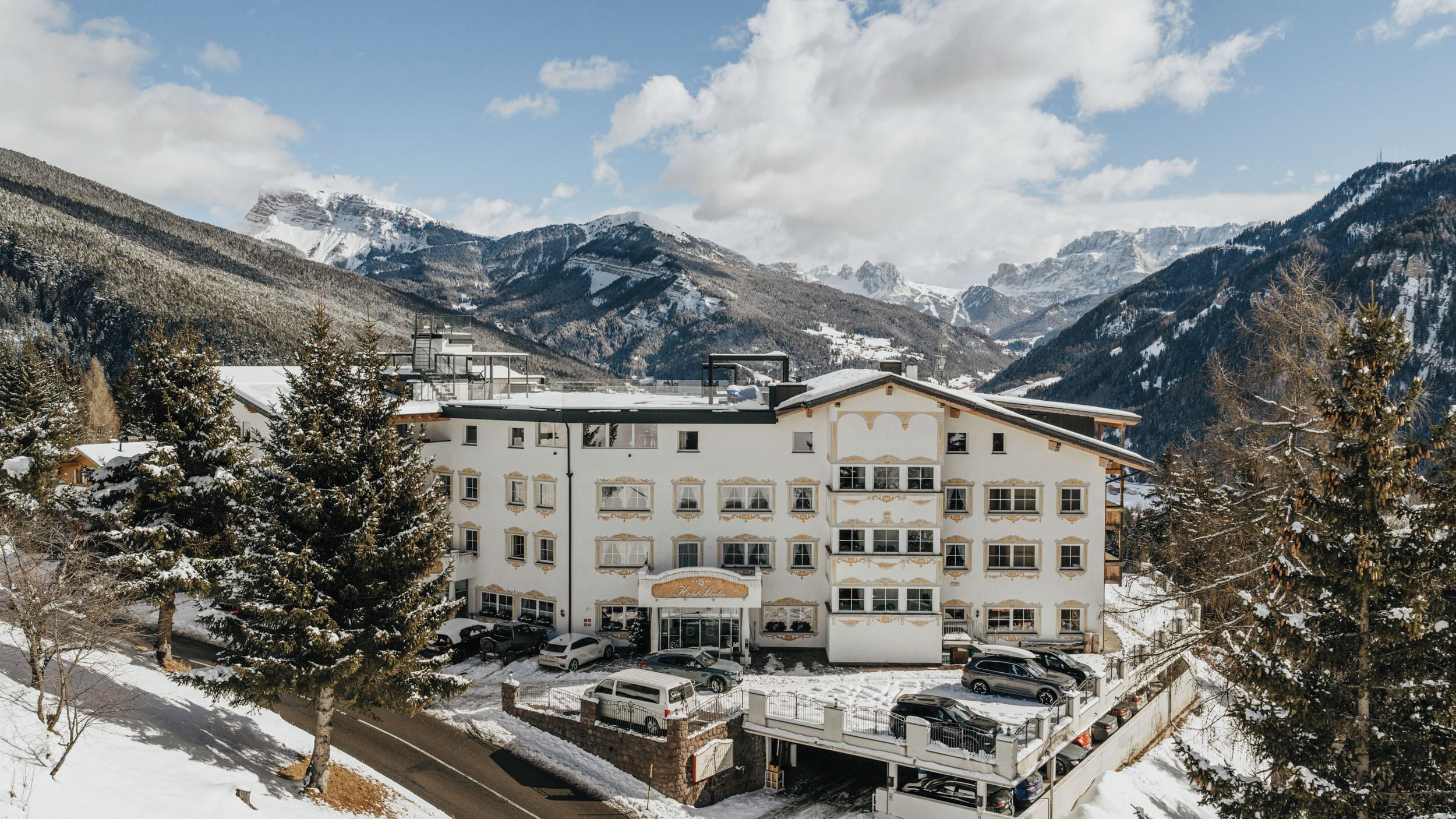 Un hotel con fachada simétrica, numerosas ventanas y un paisaje nevado con montañas al fondo.