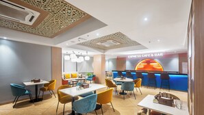Een modern restaurantinterieur met tafels en stoelen, een bar en een plafond met ingewikkelde patronen.