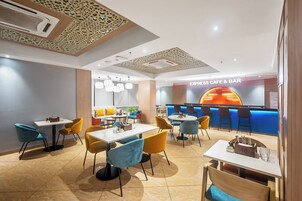 Ein modernes Restaurant mit Tischen, Stühlen, einer Bar und einer Decke mit aufwendigen Mustern.