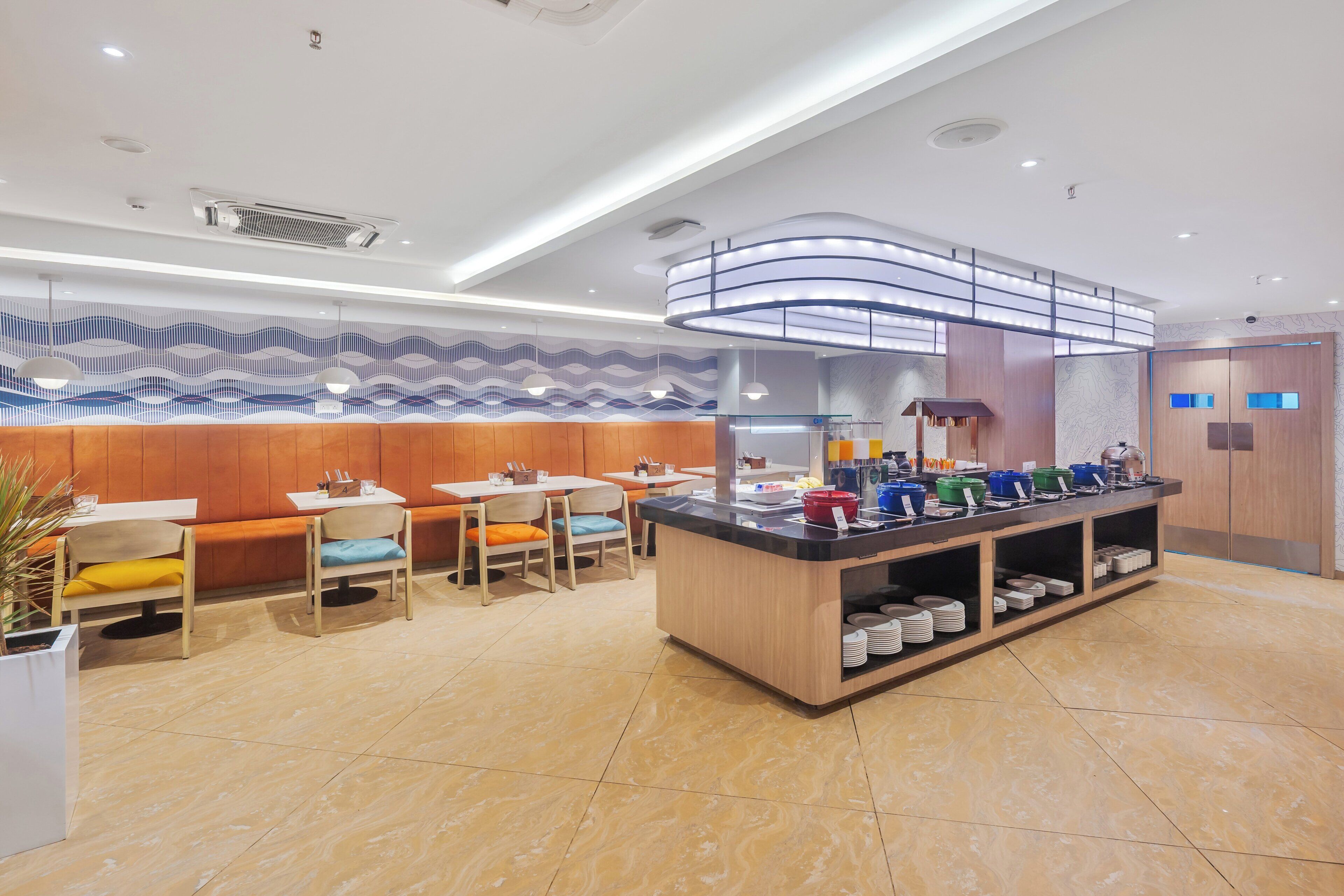 A modern restaurant with a central counter, seating area, and decorative wall.