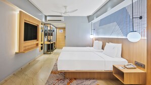 Ett modernt hotellrum med en stor säng, sängbord, en TV och en takfläkt.
