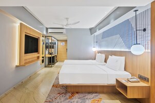 Ein modernes Hotelzimmer mit einem großen Bett, Nachttischen, einem Fernseher und einem Deckenventilator.