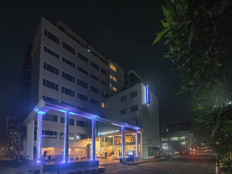 A hotel with a modern design, featuring a prominent entrance and a sign indicating it is a Holiday Inn Express & Suites.
