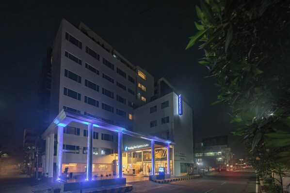 Ein Hotel mit modernem Design, das eine markante Eingangspartie und ein Schild mit der Aufschrift Holiday Inn Express & Suites zeigt.