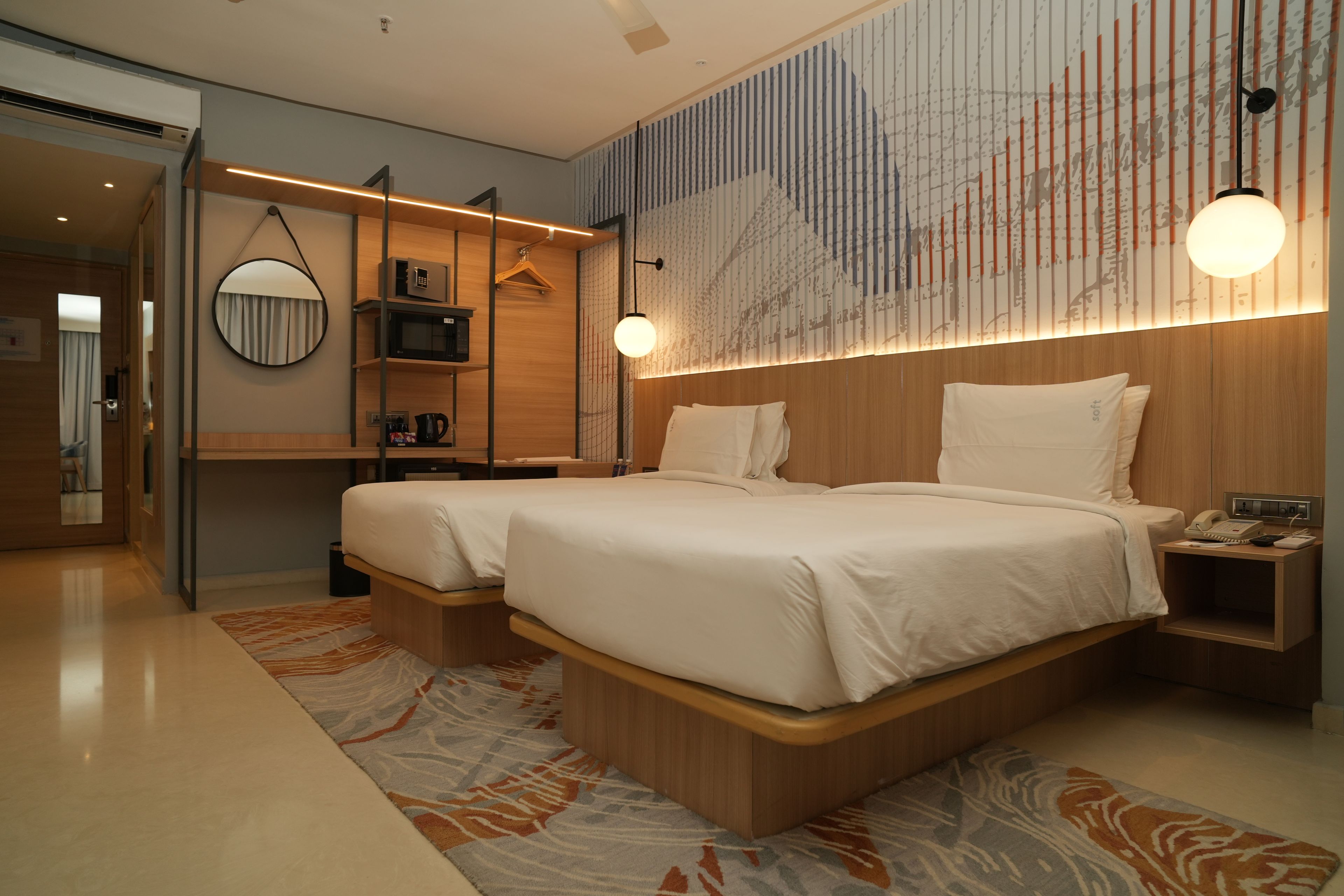 A modern hotel room with a large bed, bedside tables, a mirror, and a wall-mounted TV.