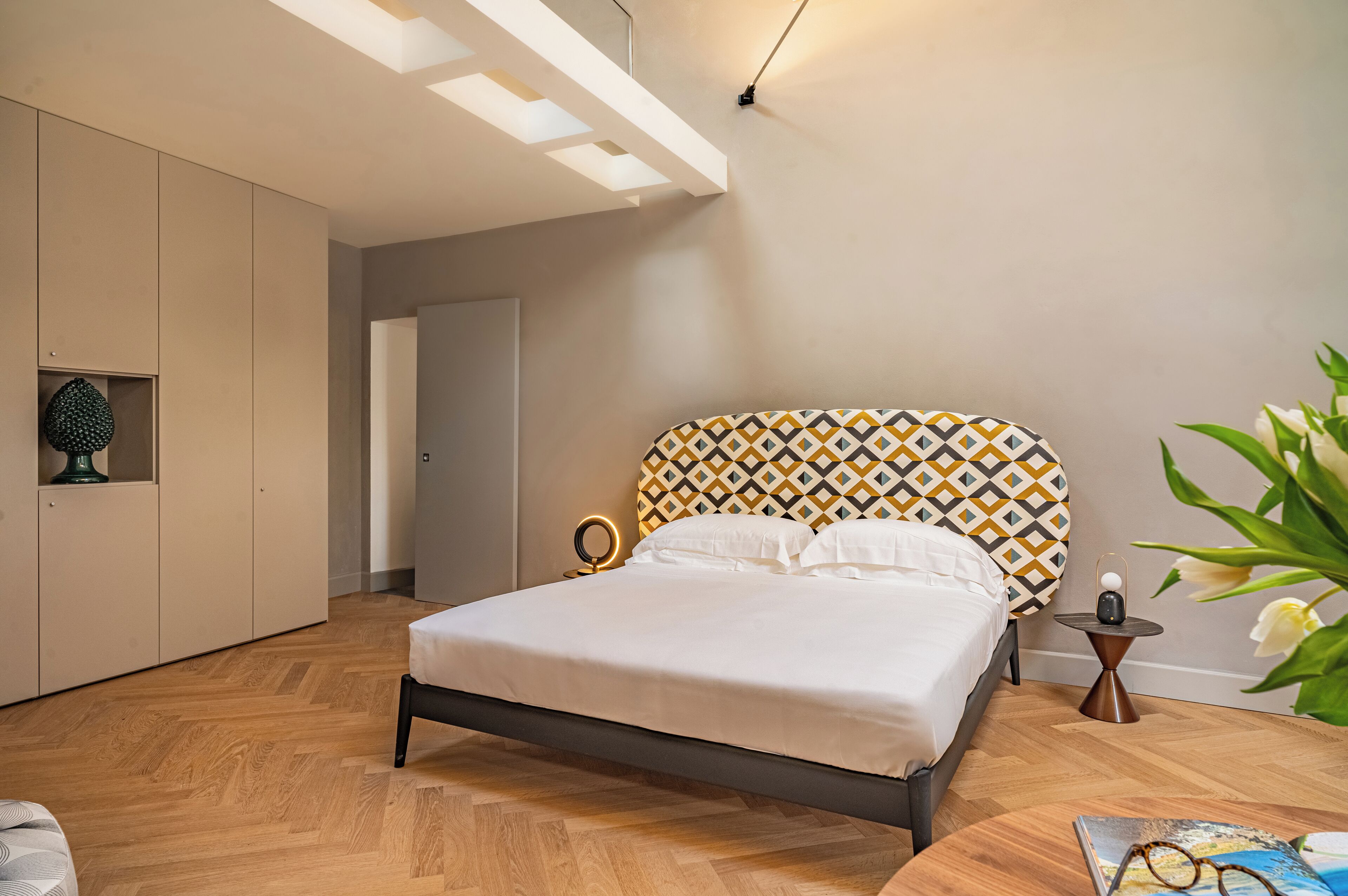 Una camera da letto moderna con un letto, un comodino con una lampada e una mensola a parete.