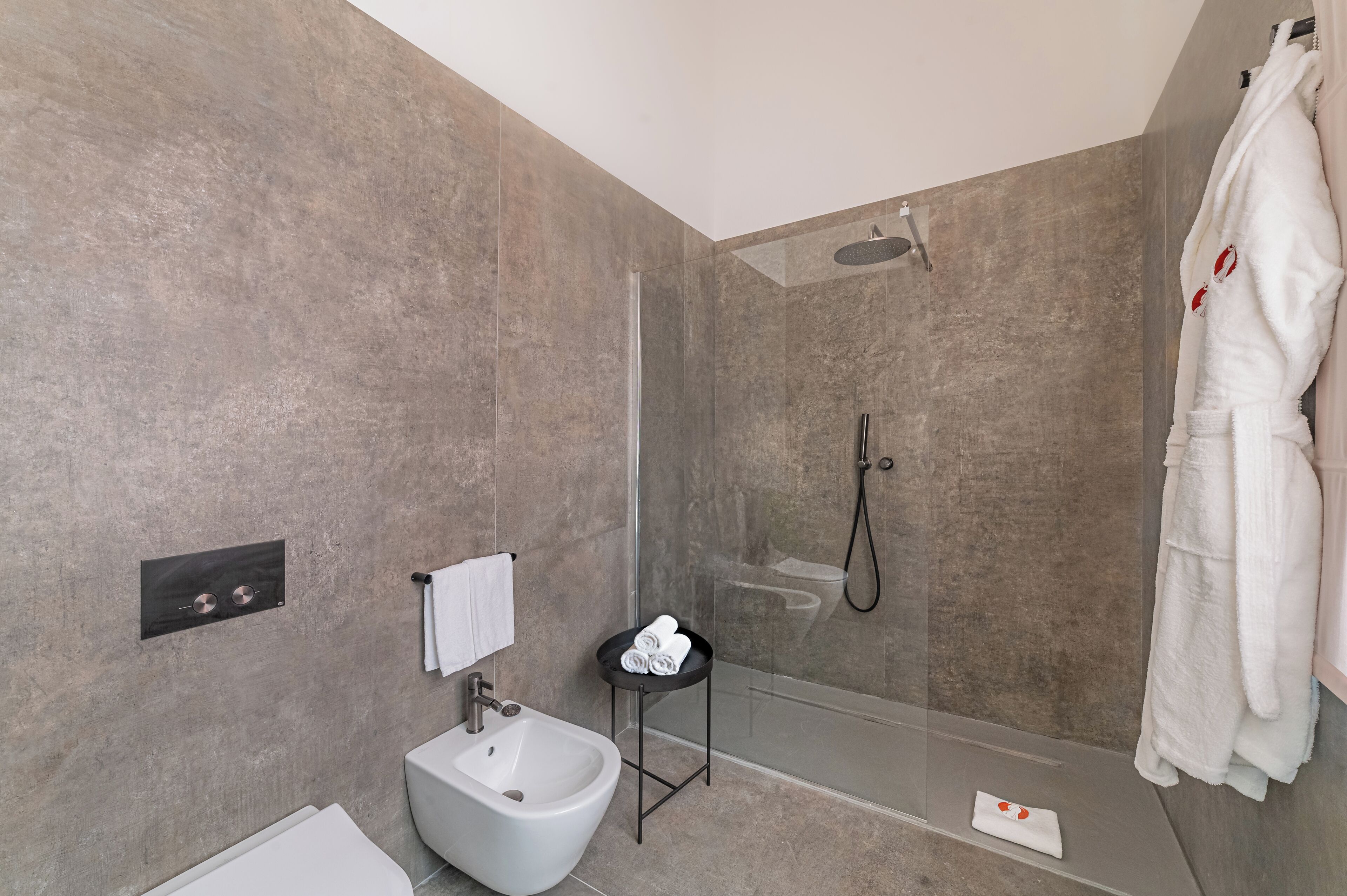 A modern bathroom with a shower, bidet, and towel rack.