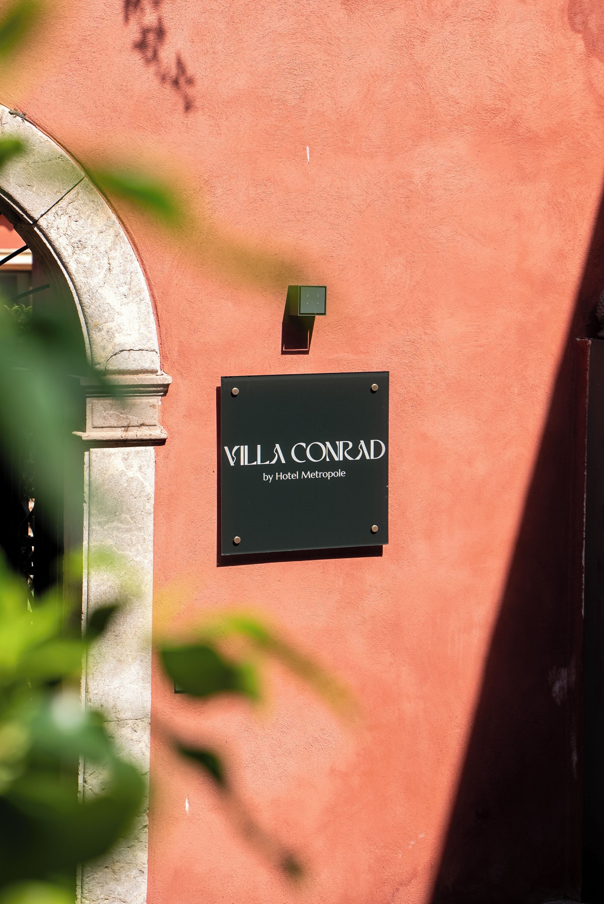 Letrero que indica 'Villa Conrad by Hotel Metropole' colocado en un edificio.