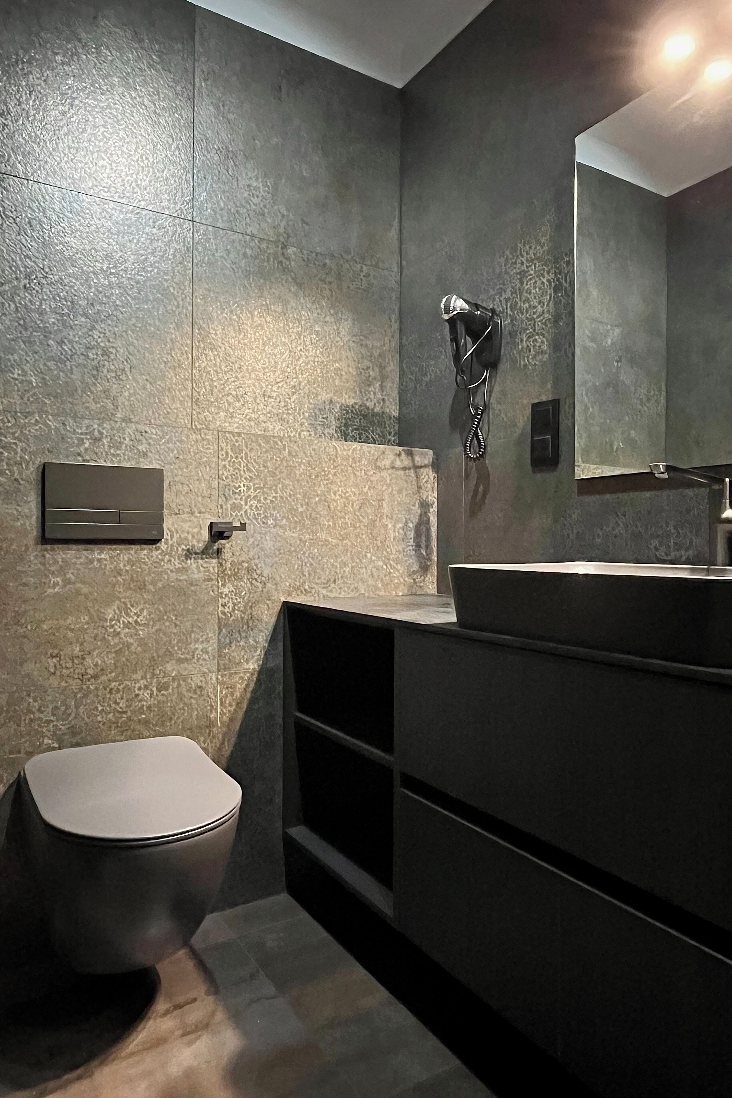 Ein modernes Badezimmer mit einem großen Spiegel, einem integrierten Waschbecken und einer Toilette.