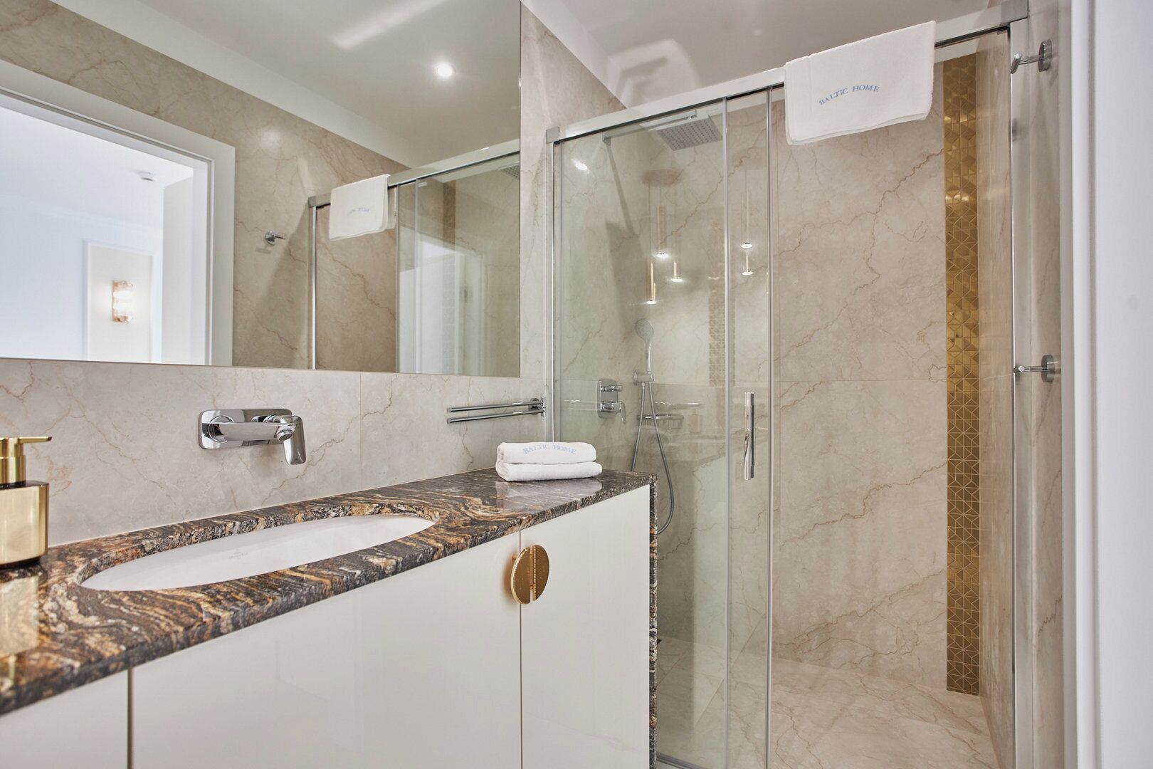 A modern bathroom with a marble sink, a glass-enclosed shower, and a large mirror.