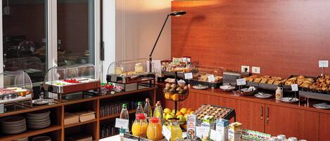 Un buffet proposant une variété de plats, notamment des fruits, des pâtisseries et des boissons.
