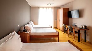 A hotel room with two beds, a desk, a chair, a TV, and a window with curtains. - Phi Hotel Homy Druento (Druento)