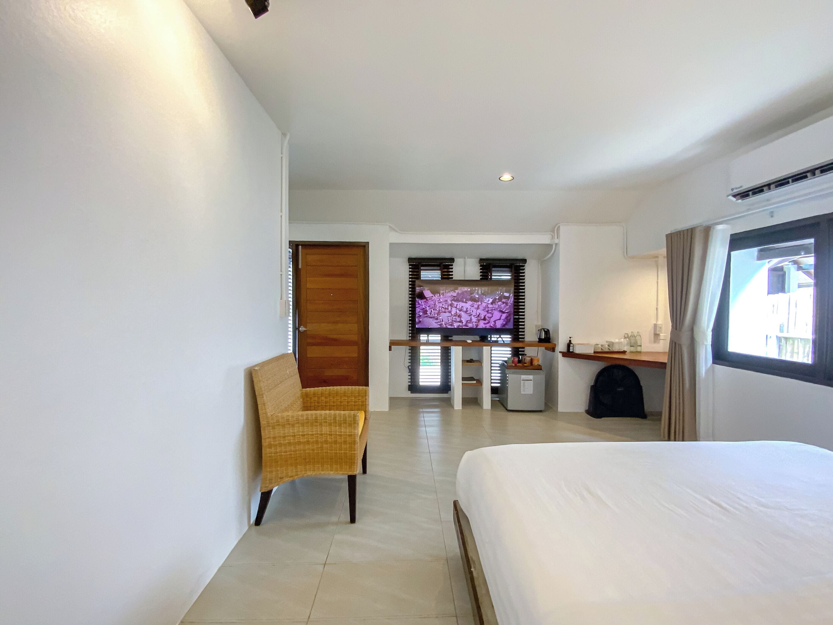 A hotel room with a bed, a chair, a TV, and a small table.