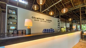 Mostrador de recepción en Chumphon Cabana Resort and Diving Center, con un letrero, una lámpara y una bolsa azul a cuadros.