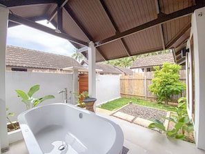 A spa area with a large bathtub, a wooden fence, and a garden. - Chumphon Cabana Resort (Pathio)