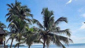 Una playa con palmeras, una estructura de madera y vista al océano.