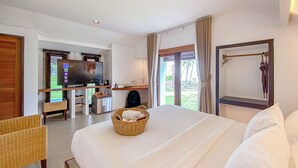 Habitación de hotel con una cama grande, televisor, escritorio con computadora y vista a la playa.