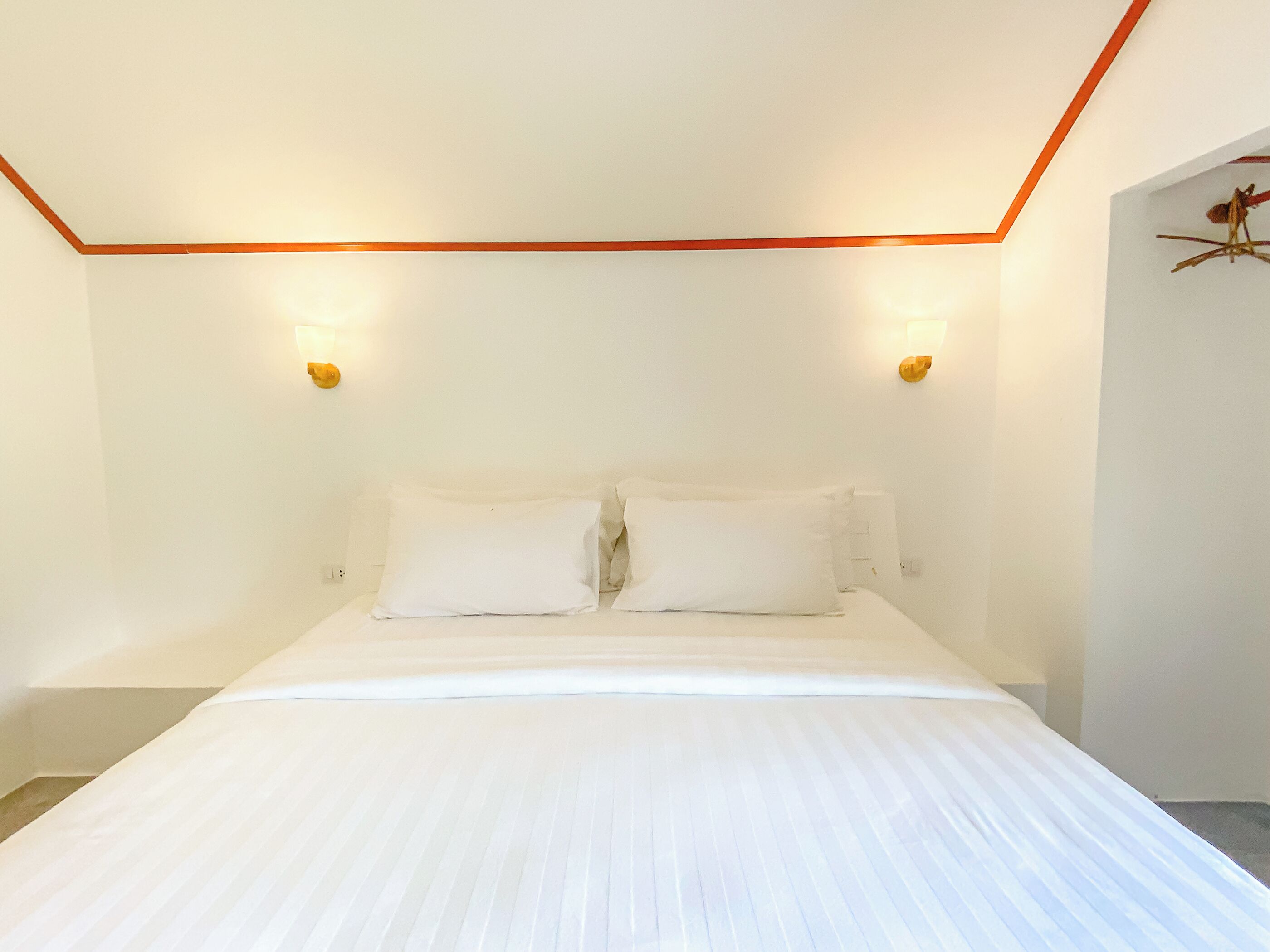 A bedroom with a large bed, two wall-mounted lights, and a simple, clean design.