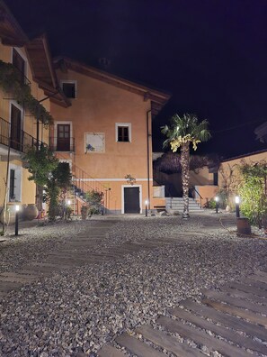 A building with a stone facade, a palm tree, and a gravel courtyard. - CASCINA D'OLTRALPE - MONGINVERO - FAMILY APARTMENT (Susa)