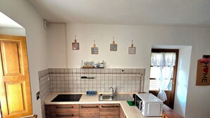 A kitchen with a wooden countertop, a sink, a microwave, and a window with curtains. - CASCINA D'OLTRALPE - MONGINVERO - FAMILY APARTMENT (Susa)