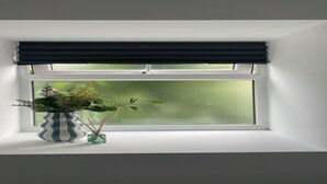 A window with a white frame, a dark window blind, a striped vase with a plant, and a small glass container with reed sticks. - Cozy Studio in Brighouse (Brighouse)