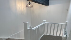 A white staircase with a geometric light fixture above. - Cozy Studio in Brighouse (Brighouse)