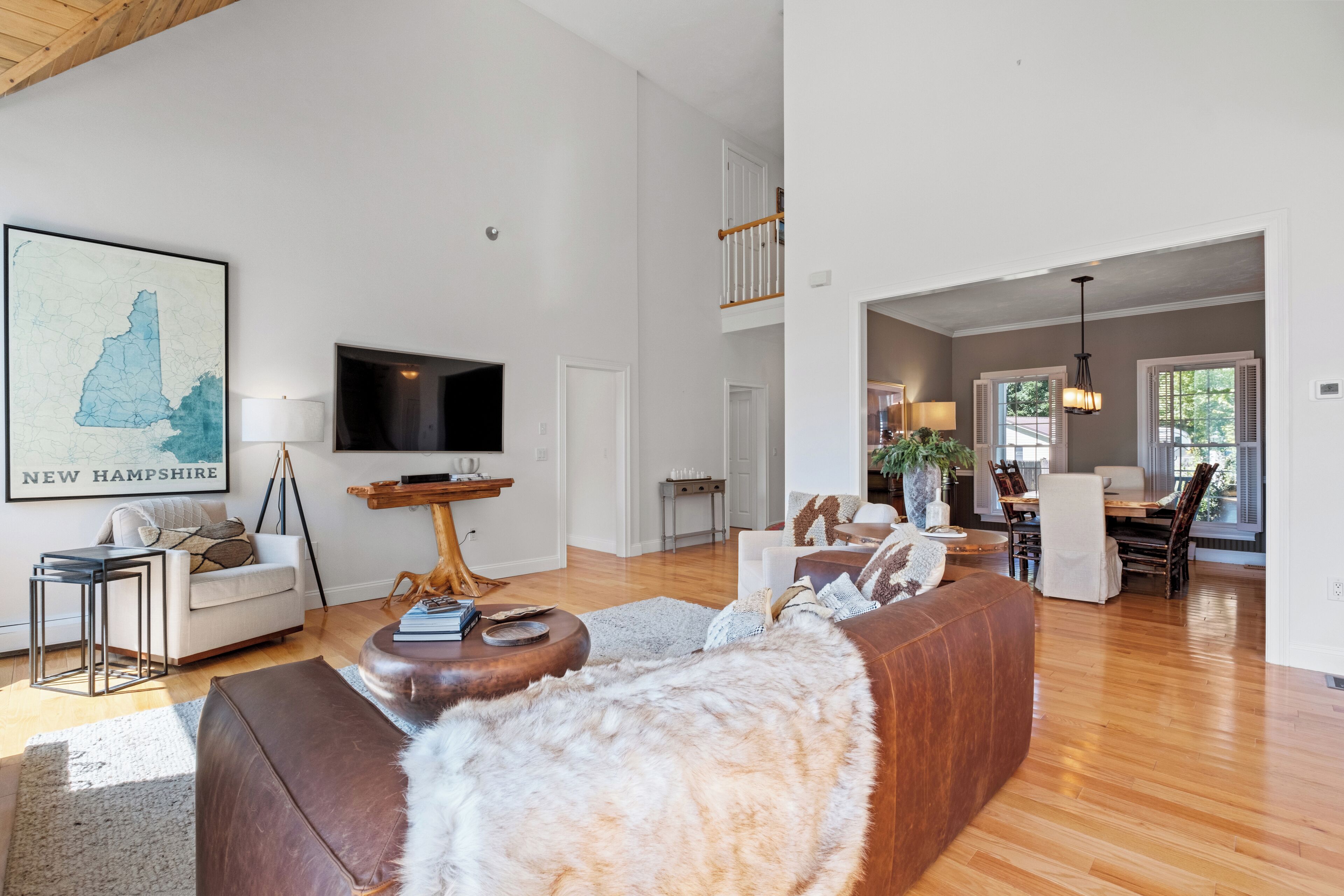 A spacious living room with a large sectional sofa, a flat-screen TV, and a dining area with a wooden table and chairs.