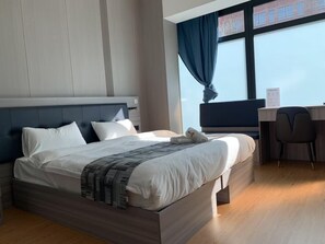 A modern hotel room with a large bed, a desk, and a view of the city through the window. - Mooncity Hotel & Boardinghouse (Frankfurt)