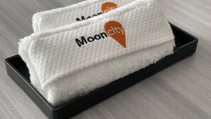 Dos toallas blancas con el bordado "Mooncity" sobre un tacón negro.