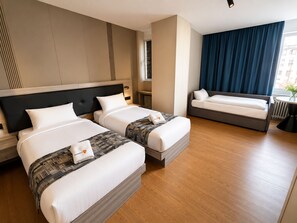 A hotel room with two beds, a sofa, a window with curtains, and a radiator. - Mooncity Hotel & Boardinghouse (Frankfurt)