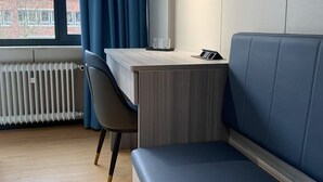 Una habitación moderna con un escritorio de madera, un sofá azul, una silla y un radiador.