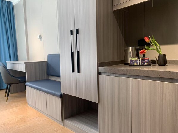 A modern hotel room with a kitchenette, a seating area with a blue cushioned bench, and a small table. - Mooncity Hotel & Boardinghouse (Frankfurt)