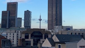 Un paisaje urbano con edificios modernos y altos, incluyendo un rascacielos destacado con un diseño puntiagudo.