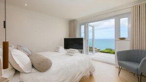 A bedroom with a bed, a TV, and a view of the sea.