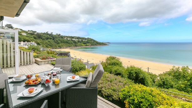 A dining table with breakfast items and a view of a beach.