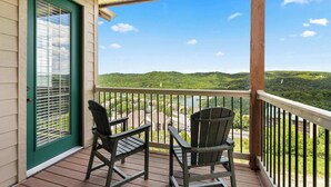 A balcony with two Adirondack chairs overlooking a scenic view of hills and a body of water.
