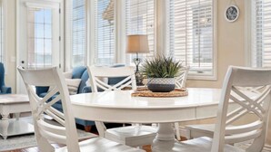 A dining area with a round table, white chairs, and a potted plant.