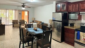 Cocina moderna con refrigerador, microondas y estufa. Cuenta con una zona de comedor con mesa y sillas.