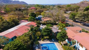 A residential area with multiple houses, a swimming pool, and a road. - Coastal Comfort: Spacious Second-Floor Getaway (Playas Del Coco)