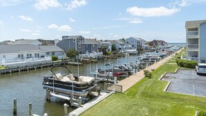Un port de plaisance avec des bateaux amarrés, une zone herbeuse et des immeubles résidentiels le long du littoral.