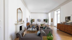 A spacious living room with a fireplace, sofas, a coffee table, and artwork on the walls. - Divisi Suites & SPA (Palermo)