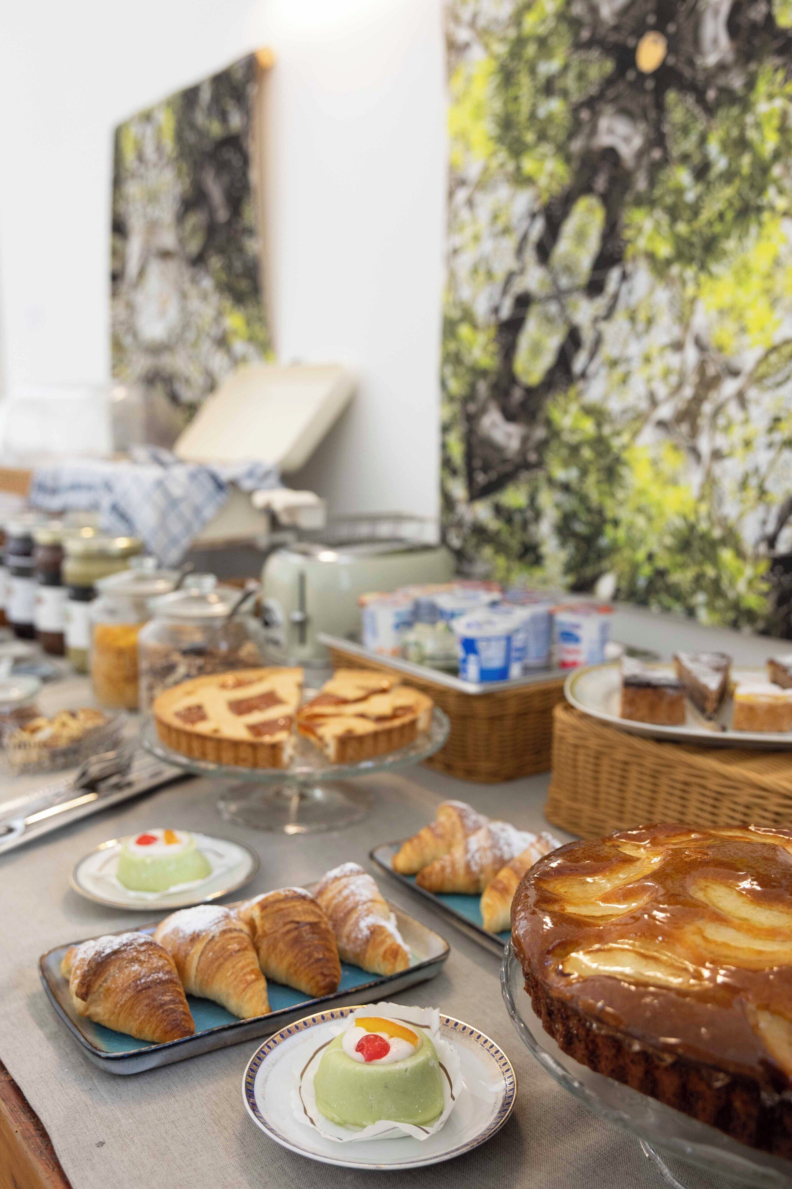 A buffet table with various pastries and desserts, including croissants, a cake, and a pie.