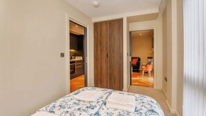 Een slaapkamer met een bed, een houten kledingkast en een zichtbare badkamer door een open deur.