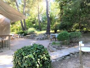 An outdoor patio with stone seating, surrounded by greenery and trees. - Casa-Amanda pinede piscine privée calme absolu (Mimet)