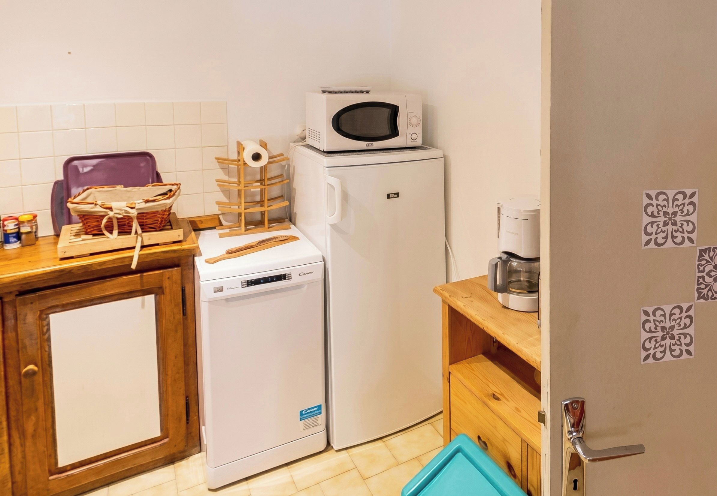 A compact kitchen with a microwave, a refrigerator, a dishwasher, and a coffee maker on a wooden countertop.